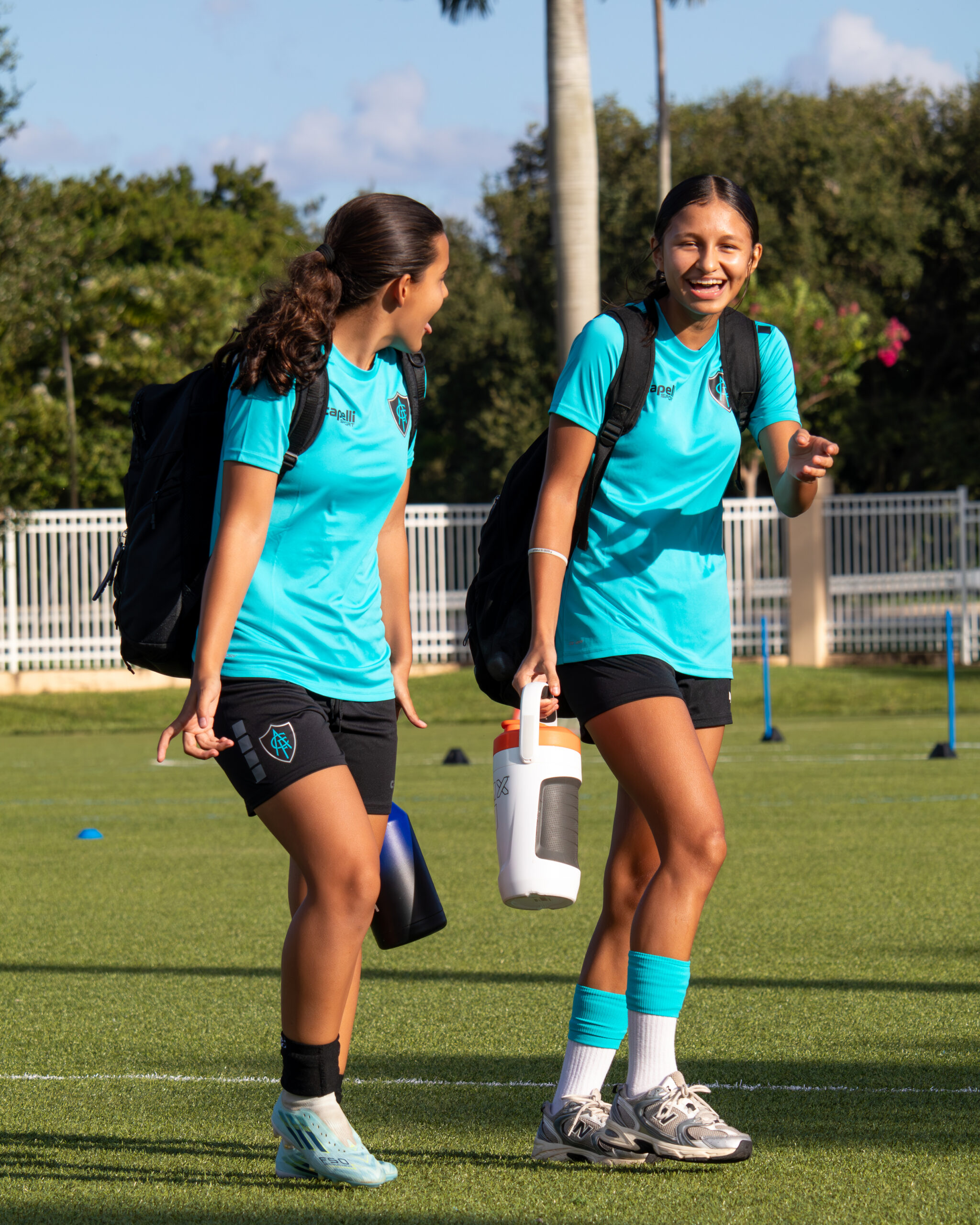 Two Acf sunrise youth soccer players in blue acf kits walking on to the field before practice at golden hour in broward county florida.